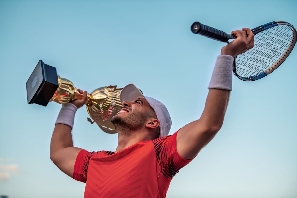 Foto di un giocatore di tennis con una racchetta da tennis e una coppa in mano