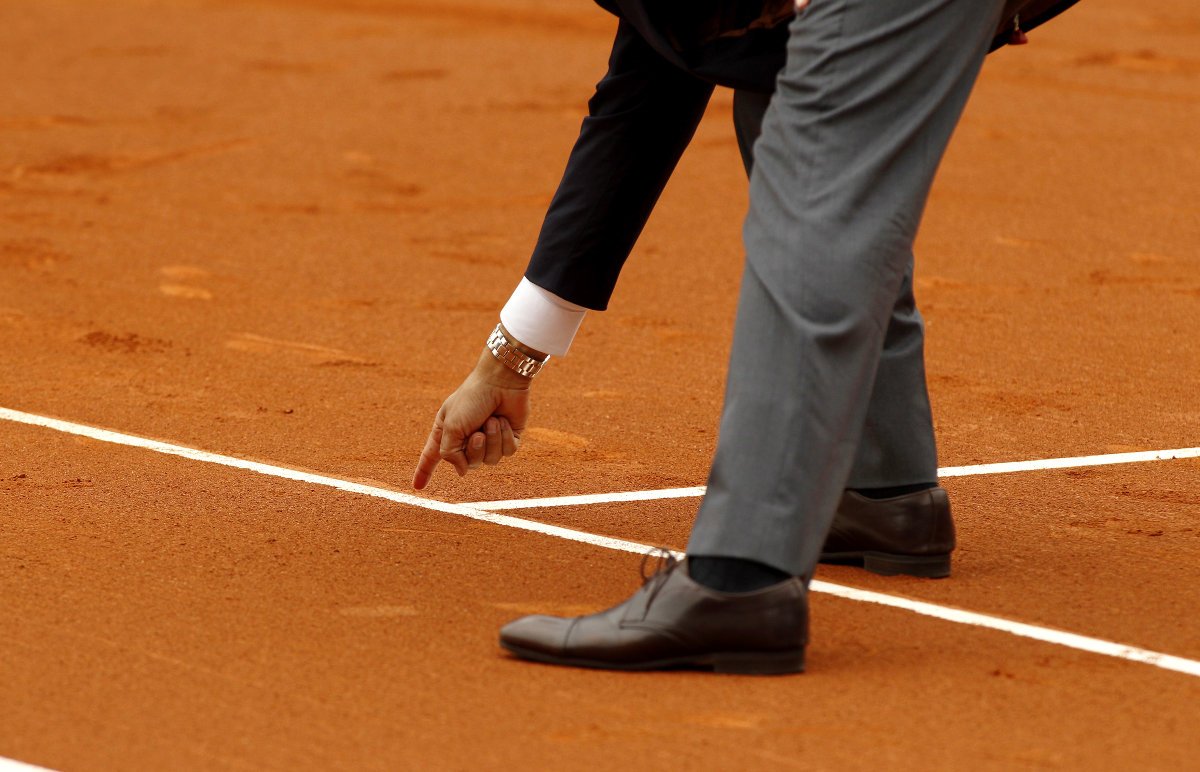 Foto de un árbitro de tenis tomando una huella en la línea