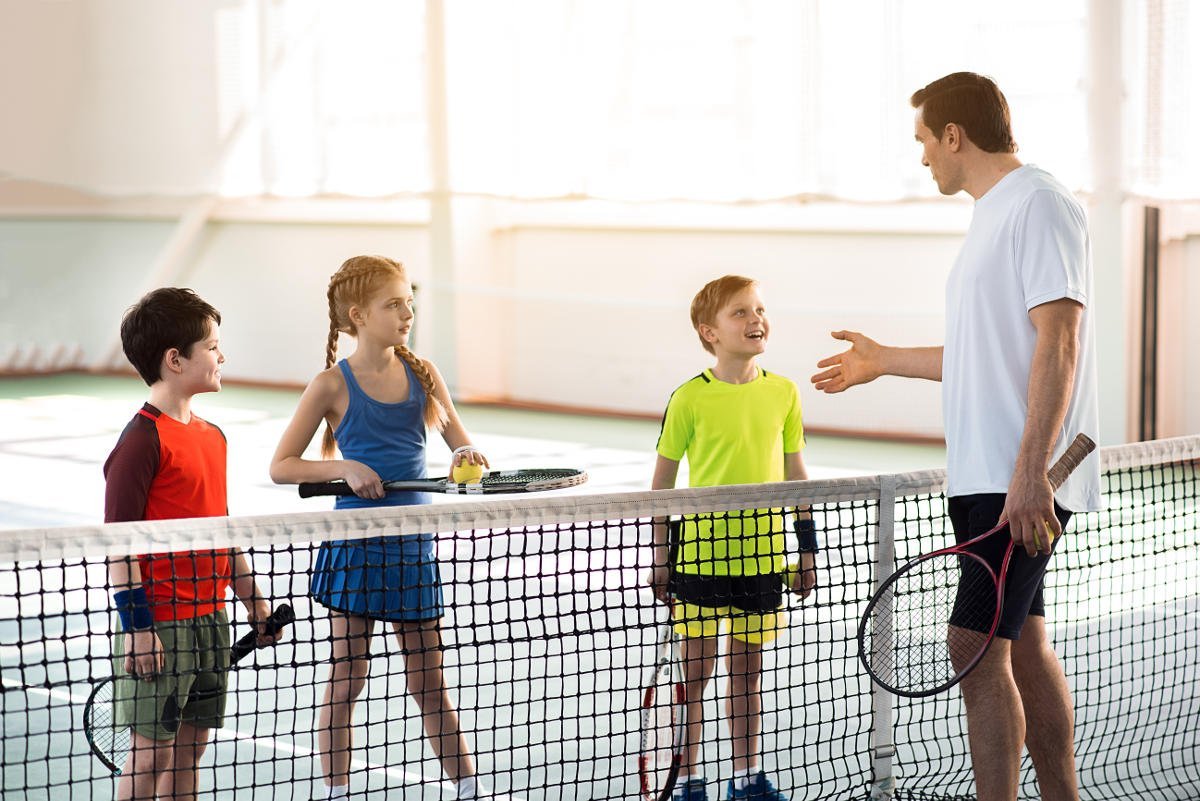 photo of a tennis coach and kids with appropriate tennis clothing