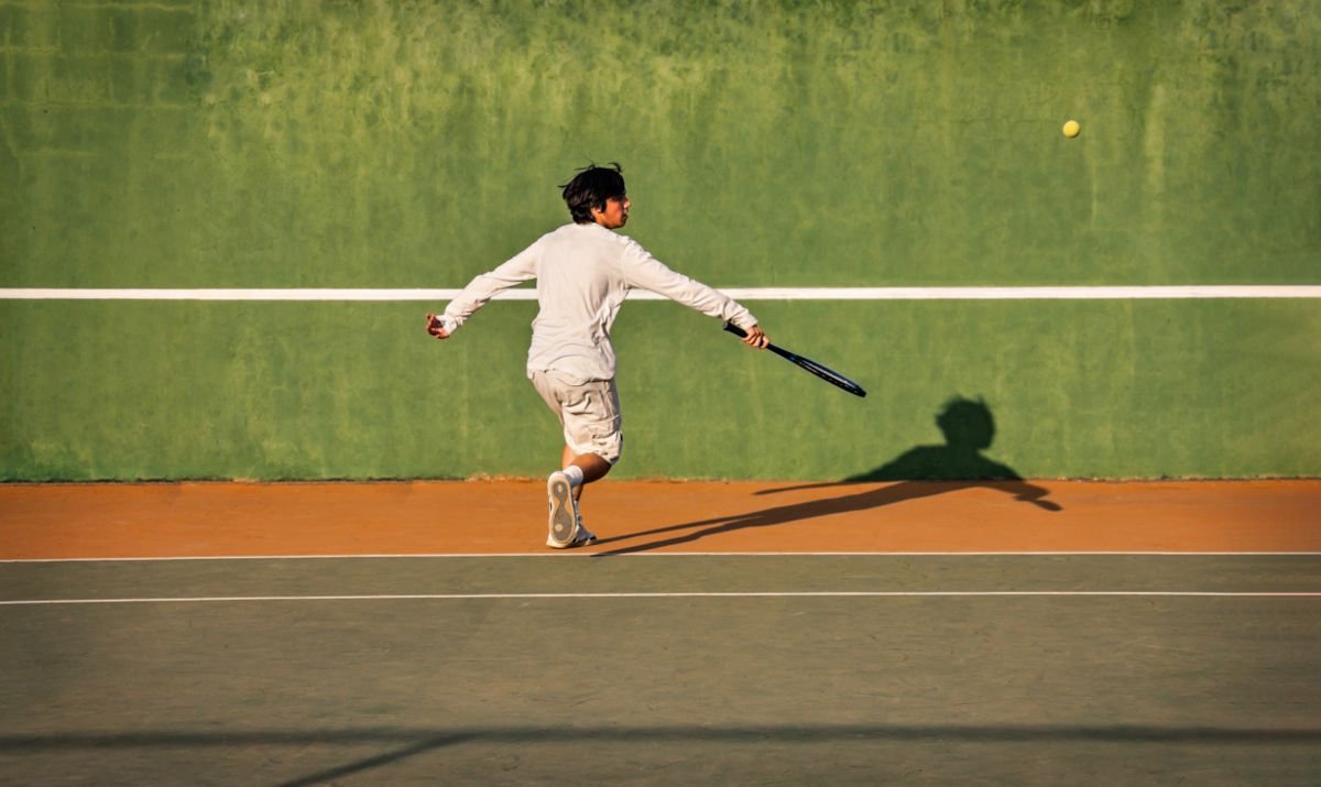 Foto van een tennisser op een tennismuur