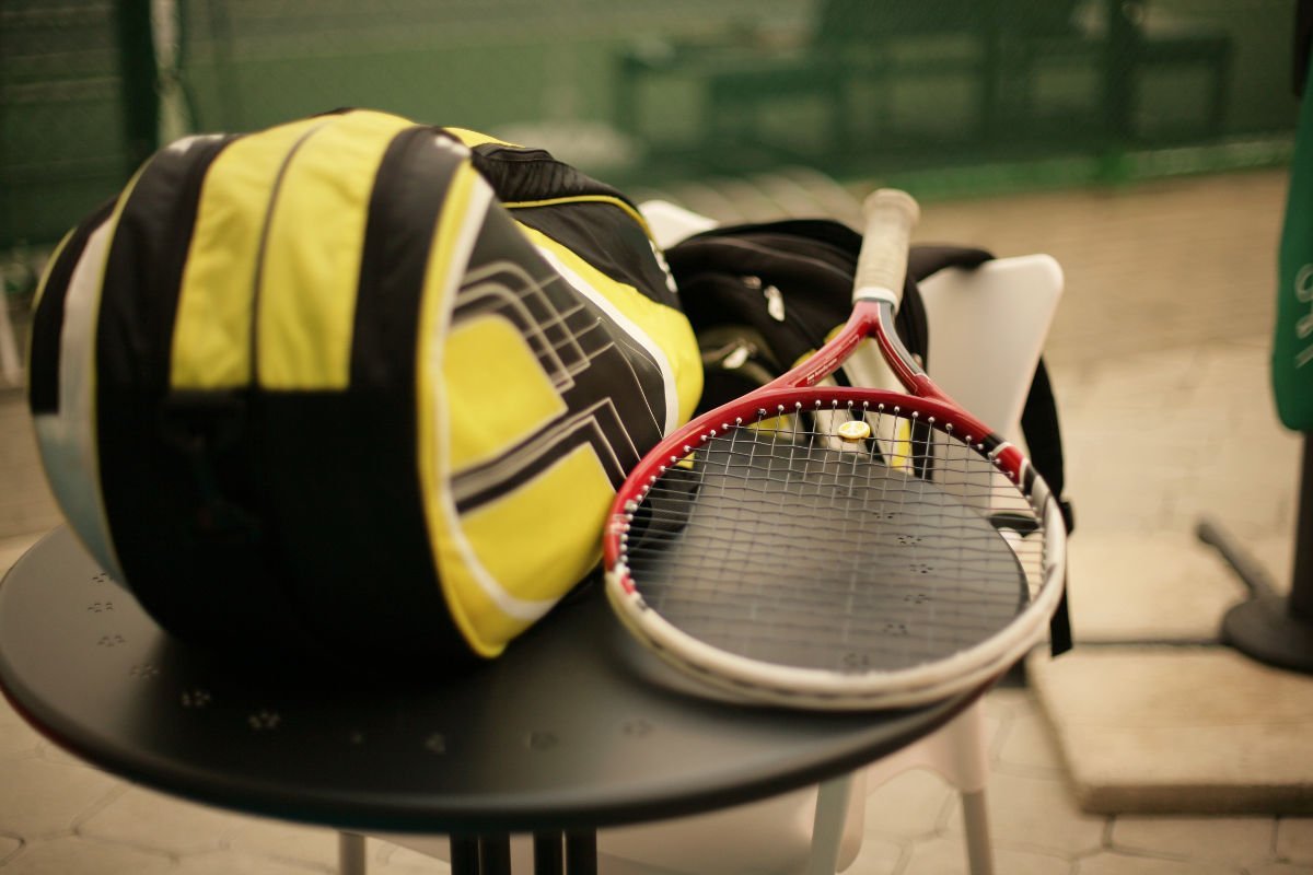 photo of a tennis bag and a tennis racket on a table