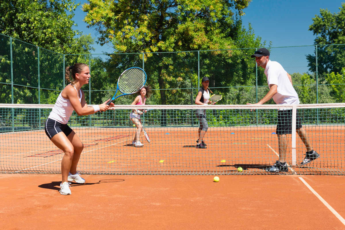 Foto van een tenniscoach met verschillende vrouwelijke tennissers